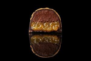 skära lyx handgjort godis med choklad och gul confiture fyllning på svart bakgrund. foto