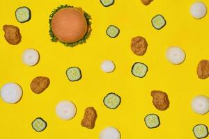 mest populär snabb mat måltid. kyckling klumpar, burger med färsk gurka och lök på gul bakgrund topp se foto