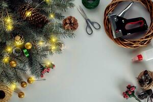 jul bakgrund med dekorationer, krans och tall kottar. skapande krans tillverkad av jul träd grenar på vit bakgrund. foto