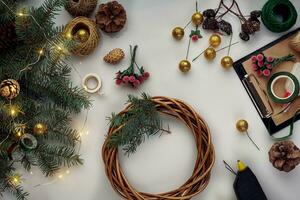 jul bakgrund med dekorationer, krans och tall kottar. skapande krans tillverkad av jul träd grenar på vit bakgrund. foto