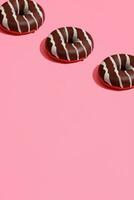 mat design med gott choklad glaserad munk med vit remsor på korall rosa pastell bakgrund topp se mönster foto