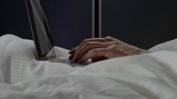 fingrar av mannen att skriva på bärbara datorn på sängen foto
