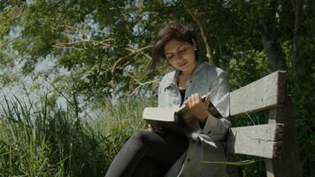kvinnasammanträde på träbänk i landet som läser en bok foto