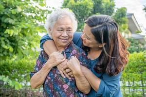 asiatisk äldre kvinna med vårdgivare som går med glad i naturparken.