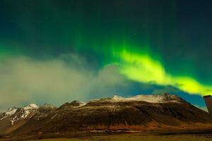 i Island, aurora borealis ljusnar mörk horisont runt om solnedgång med magnifik färger av grön och lila, formning unik isländsk miljö. runt om nordlig lampor, stjärnor gnistra. foto