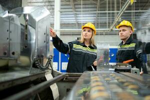 både av ingenjör arbetare arbetssätt på en maskin i en fabrik. industriell bakgrund foto