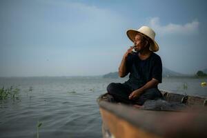 en fiskare slappnar av i en båt på de sjö medan rökning. foto