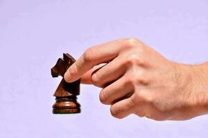 hand av en man innehav en schack bit foto