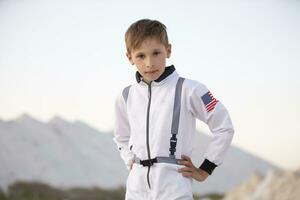 en ung pojke klädd som ett astronaut mot de bakgrund av vit bergen och blå himmel. foto
