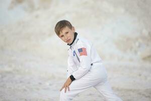 ung pojke klädd som ett amerikan astronaut Framställ mot de bakgrund av de vit berg. foto