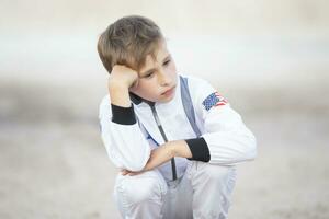 ledsen pojke klädd som ett amerikan astronaut. foto