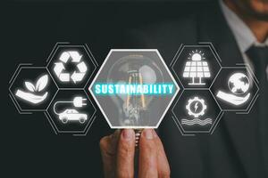 hållbarhet begrepp, affärsman hand innehav ljus blub med hållbarhet ikon på virtuell skärm. foto