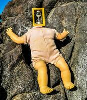 en docka med en gul låda på dess huvud om på en sten foto
