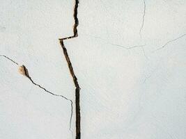 sprickor i de cement vägg vit cement av byggnader skadad förbi jordbävningar foto
