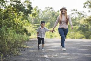 närbild av glad mamma och son som håller handen i en park. familjekoncept. foto