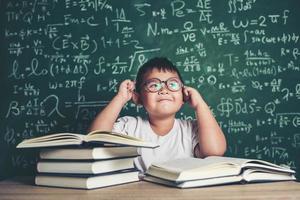 tankeväckande liten pojke med bok i klassrummet