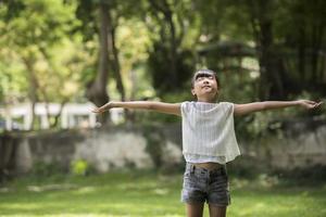 glad liten flicka visar upp handen i luften i trädgården foto