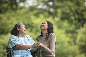 barnbarn pratar med sin mormor som sitter på rullstol foto