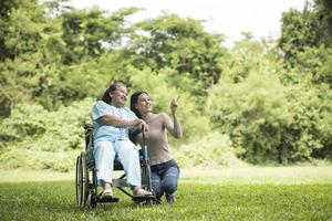 barnbarn pratar med sin mormor som sitter på rullstol foto