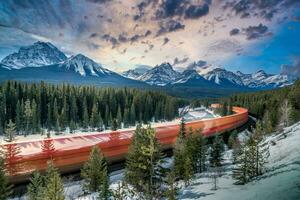 en tåg reser genom de bergen med snö täckt träd foto