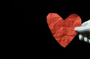 en person innehav en röd hjärta formad papper foto