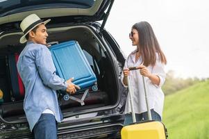asiatisk man som hjälper kvinnan att lyfta resväska från bilen