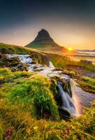 soluppgång över Kirkjufell berg med vattenfall strömmande och vild blomma blomning i sommar på island foto