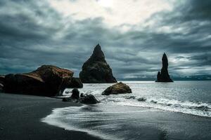 lynnig reynisdragar naturlig sten bildning på reynisfjara svart sand strand i atlanten hav på island foto