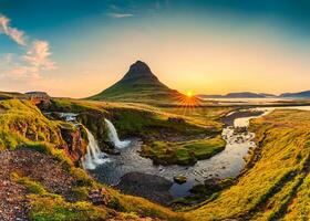 soluppgång över vulkanisk Kirkjufell berg med vattenfall strömmande i sommar på island foto