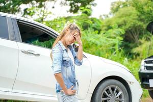 ung kvinna stå Nästa till henne bil och känsla ledsen i de skadad bil efter en bil olycka. foto