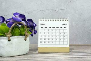 vit kalender på kontor trä- skrivbord med inlagd växt. 2024 ny år begrepp foto