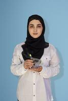 ung muslim kvinna bär traditionell abaya Kläder innehav i händer miniatyr- handla vagn. söt muslim kvinna i hijab innehar en handla vagn foto