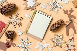 topp se av anteckningsbok omgiven med ny år leksaker och dekorationer på orange bakgrund. jul tid begrepp foto