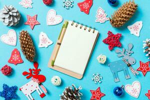 topp se av anteckningsbok omgiven med ny år leksaker och dekorationer på blå bakgrund. jul tid begrepp foto