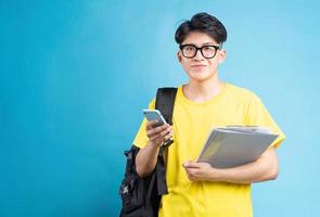 asiatisk manlig studentporträtt, isolerad på blå bakgrund foto