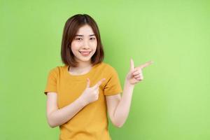 ung asiatisk tjej poserar på grön bakgrund