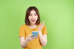 ung asiatisk tjej poserar på grön bakgrund foto