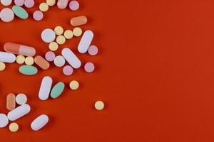 grupp olika tabletter piller kapslar på röd bakgrund.