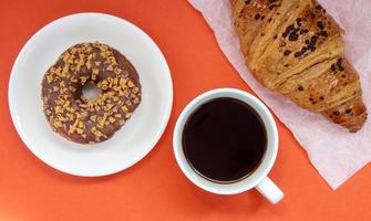 en chokladmunk, croissant och svart americano -kaffe foto