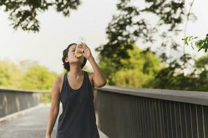 kvinna dricka energi dryck efter joggning i de parkera. foto