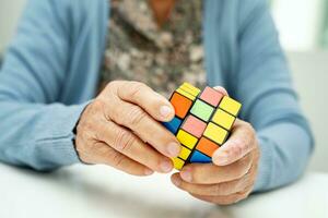 Bangkok, thailand augusti 14, 2023 alzheimers sjukdom annons, asiatisk äldre kvinna patient spelar rubik kub spel till öva hjärna Träning för demens förebyggande. foto