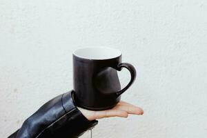 hand innehav en kopp med en hjärtformade hantera. svart färgad kaffe eller tekopp med hand i hjärta form foto