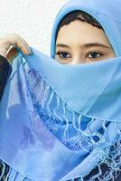 närbild porträtt av skön iranian flicka med blå ögon. attraktiv muslim kvinna i hijab beläggning henne ansikte med scarf foto