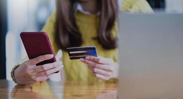 ung kvinna som betalar online med smartphone och kreditkort. foto