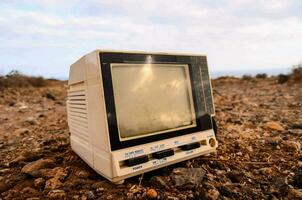 ett gammal tv sitter på de jord i en fält foto