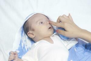 mor hand rörande de näsa av en bebis pojke foto