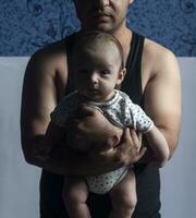 Brutal far med hans nyfödd unge. pappa innehav hans nyfödd bebis foto