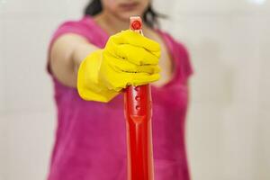 kvinna med spray rengöringsmedel. hemmafru innehav röd spray flaska på badrum. rengöring bad foto