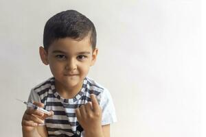 en liten dålig pojke innehav spruta och kallelse någon med hans finger. en unge har roligt på sjukhus foto