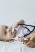 liten söt bebis läkare. 6 månader gammal bebis pojke spelar med stetoskop. unge har roligt tycka om en läkare foto